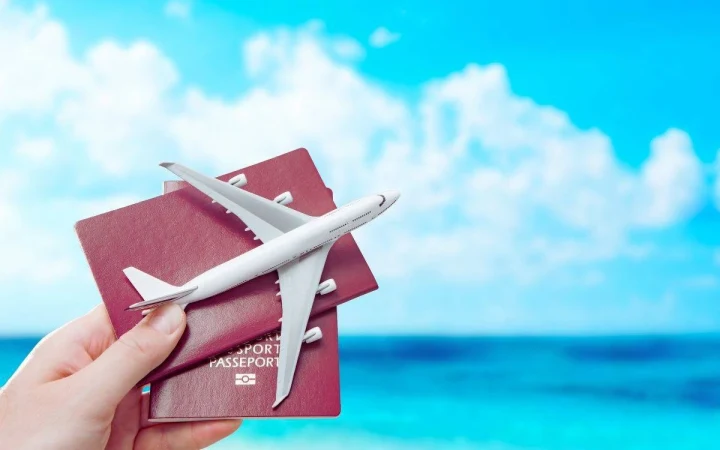 Bir elin tuttuğu pasaportların üzerinde oyuncak yolcu uçağı