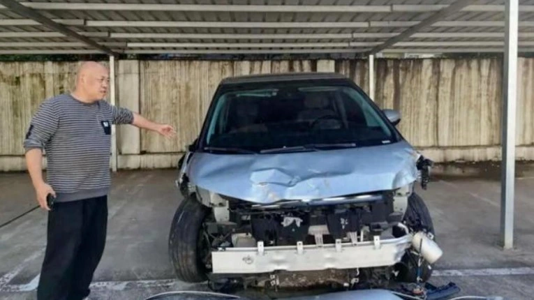 Ön kısmı ağır hasarlı Xpeng X9’un yanında duran kişi