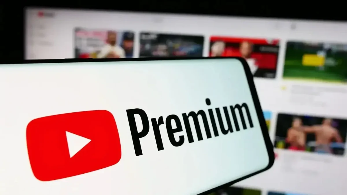 YouTube Premium logosu, bir telefon ekranında video platformunun arayüzü önünde görülüyor