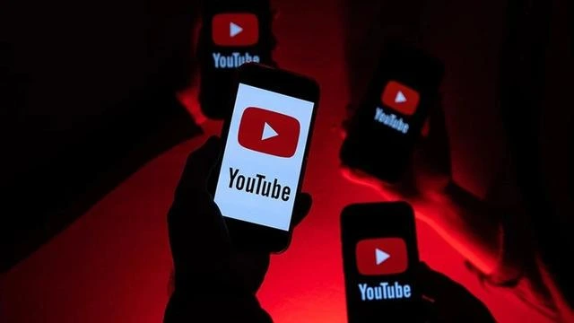 Kırmızı ışık altında YouTube logosu görünen telefonları tutan kişiler